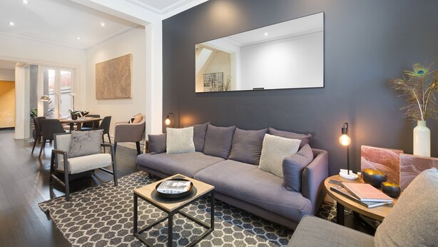 Un salon moderne avec un canapé gris, une table basse et un coin repas à l’arrière-plan.