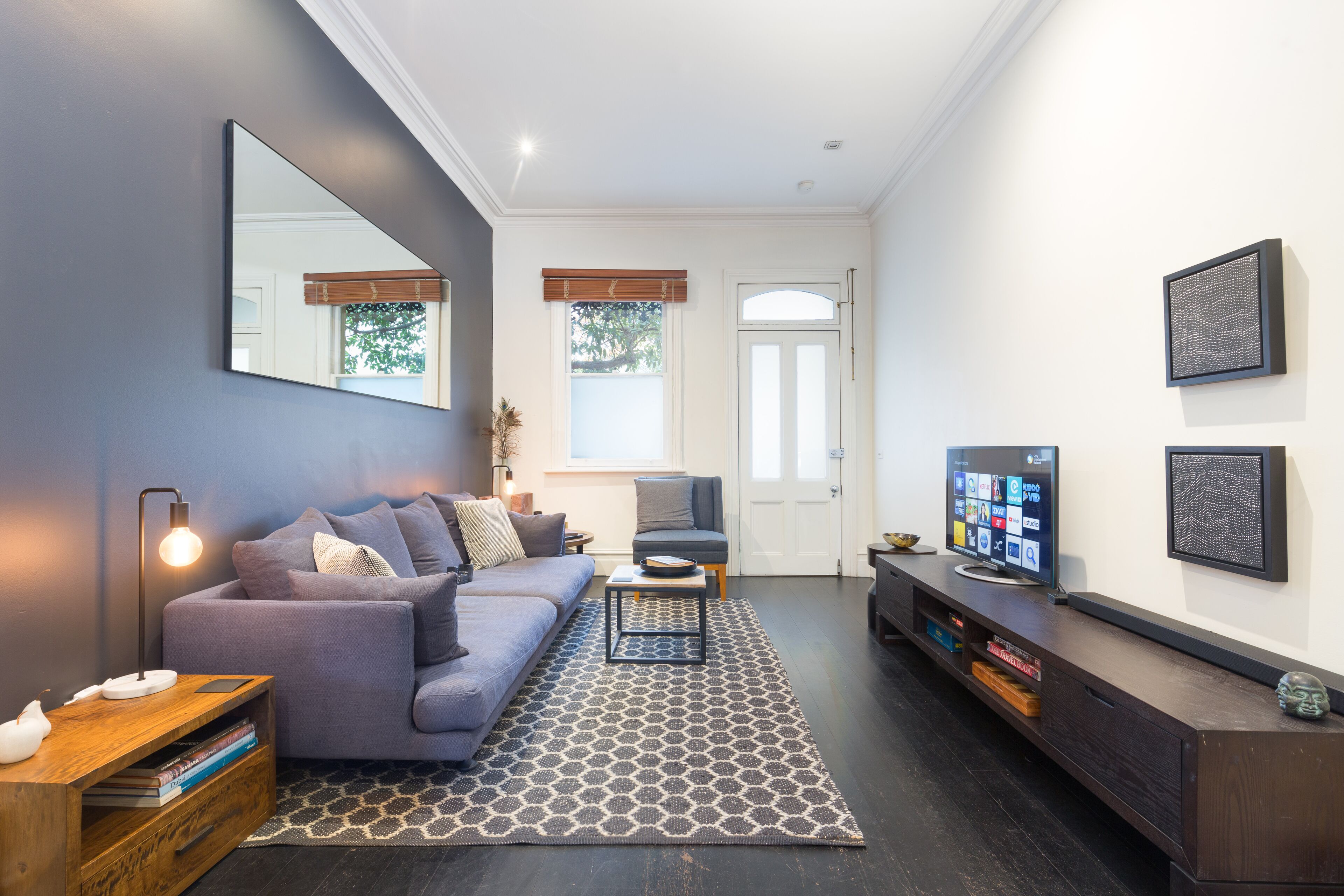A modern living room with a grey sofa, a coffee table, and a TV on a wooden stand.