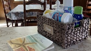 A dining area with a table set for two, a wicker basket labeled "Clean," and a notebook with a starfish design. - Windsurfers Cove, shore front cottage (Tiverton)