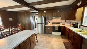 A kitchen with wooden cabinets, a stainless steel refrigerator, a built-in oven, and a marble countertop. - Windsurfers Cove, shore front cottage (Tiverton)
