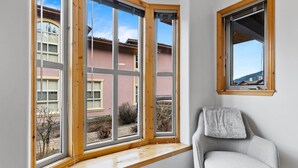 Ein Eckzimmer mit großem Fenster und Blick auf ein Gebäude mit vielen Fenstern.