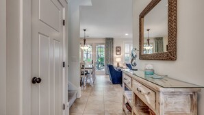 A hallway with a wooden cabinet, a large mirror, and a dining area with chairs and a table. - Stunning Home with Screened Porch in North Beach Resort & Villas - 500 Yards to Pools/Beach (North Myrtle Beach)