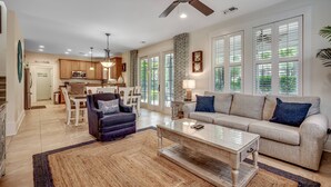 A spacious living room with a ceiling fan, a sofa, a coffee table, and a dining area in the background. - Stunning Home with Screened Porch in North Beach Resort & Villas - 500 Yards to Pools/Beach (North Myrtle Beach)