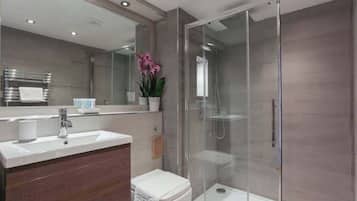 A modern bathroom with a glass-enclosed shower, a white sink, and a large mirror.