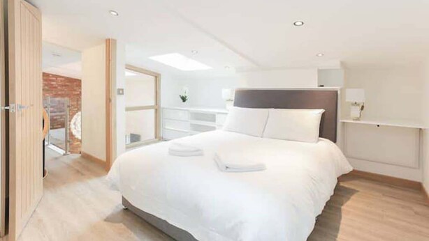 A modern hotel room with a large bed, a wooden door, a white wall, and a skylight. - LN Collection - Grassmarket (Edinburgh)