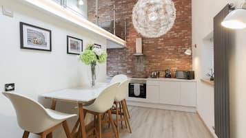 A modern kitchen with white cabinetry, a brick accent wall, and a hanging light fixture.