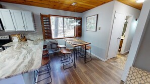 Eine Küche mit Marmorarbeitsplatte, Holzstühlen, einem Tisch und einem Fenster mit Jalousien.