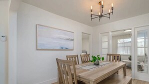 A dining area with a wooden table, six chairs, a chandelier, and a painting on the wall. - A Modern Minimalist's Dream- near DT, UNR & FWY (Reno)