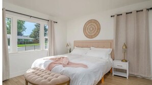 A bedroom with a bed, bedside tables, a window with curtains, and a wall decoration. - A Modern Minimalist's Dream- near DT, UNR & FWY (Reno)