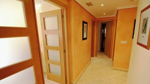 A hallway with wooden doors and framed pictures on the walls. - Puerto Romano II 88 by homeprive (Denia)