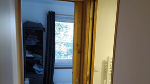 Een smalle gang die leidt naar een slaapkamer met een bed, een radiator en een kledingkast.