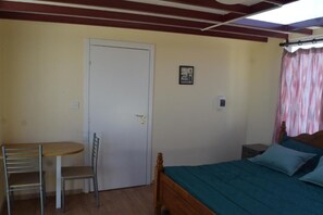 A bedroom with a wooden bed, a small bedside table, a chair, and a door.