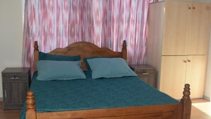 A wooden bed with a teal bedspread and two pillows, a wooden wardrobe, and a nightstand with a drawer. - *MERSINERA PARADISE GARDEN STARS HOUSE* (Kivisili)
