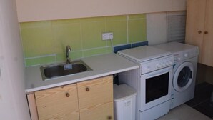A compact kitchen with a sink, wooden cabinets, a washing machine, and a dryer. - *MERSINERA PARADISE GARDEN STARS HOUSE* (Kivisili)