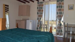 A bedroom with a bed, a wardrobe, a small fridge, and a dining area with chairs and a table. - *MERSINERA PARADISE GARDEN STARS HOUSE* (Kivisili)