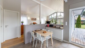 Una cocina moderna con una isla central, muebles blancos y vistas al exterior.