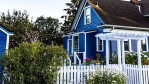 A blue house with a white picket fence, a covered porch, and a brick garden bed. - Amazing Victorian 4BR w/Hot Tub 5 Min to Downtown (Bellingham)