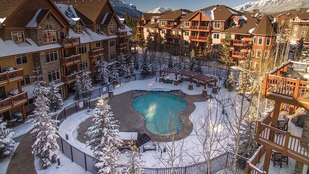 Um resort com vários edifícios, uma piscina central e paisagem coberta de neve.