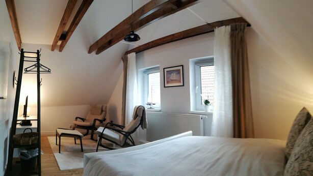 A bedroom with a bed, two chairs, a coat rack, and a radiator. - Gemütliche, Frisch Renovierte Wohnung Direkt am Elsflether Weserdeich (Elsfleth)