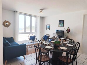 A dining area with a round table, chairs, and a TV.