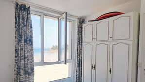 Une chambre avec un lit, une armoire et une fenêtre donnant sur la plage.