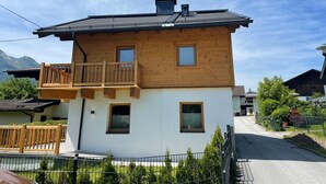 Une maison en bois à deux étages, dotée d’un balcon, d’une cheminée et d’une petite fenêtre à l’étage supérieur.