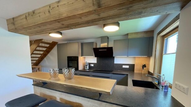 Une cuisine moderne dotée d’un îlot central, de tabourets de bar et d’un plafond en bois.