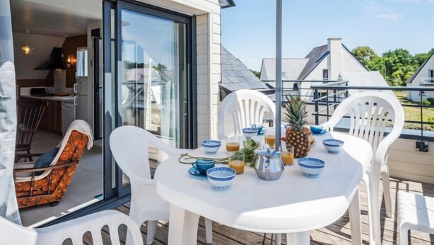 A patio with a round table, white chairs, and a large umbrella. - Kerisper by Interhome (La Trinité Sur Mer)
