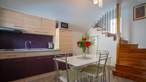 A modern kitchen with wooden cabinets, a dining table with chairs, and a staircase. - Vacation home Veli by Interhome (Opatija/Veli Brgud)