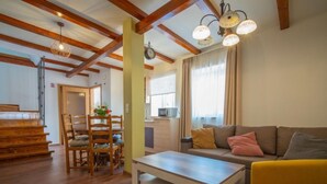 A spacious living room with wooden floors, a dining area with a wooden table and chairs, a sofa with cushions, and a kitchen in the background. - Vacation home Veli by Interhome (Opatija/Veli Brgud)