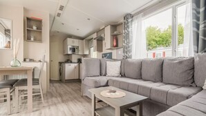 Una sala de estar moderna con un sofá seccional gris, una mesita y un comedor con una mesa y sillas blancas.