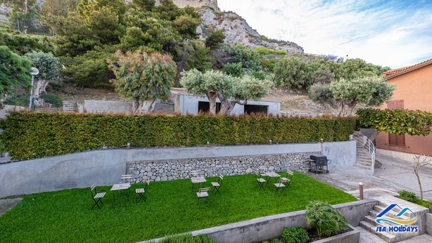 A courtyard with outdoor seating, a stone wall, and a view of a historic building.