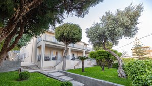 A two-story building with a balcony, a staircase, and a well-maintained lawn.