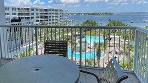 Un balcon donnant sur une piscine, un bâtiment blanc et une étendue d’eau.