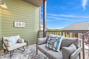 A covered outdoor seating area with two sofas, a small table, and a decorative wall piece.