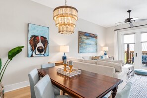 A dining area with a wooden table, chairs, a chandelier, and artwork on the walls.