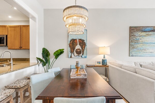 A dining area with a wooden table, chairs, a chandelier, and artwork on the walls.