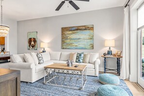 A modern living room with a white sofa, a wooden coffee table, and a blue patterned rug.