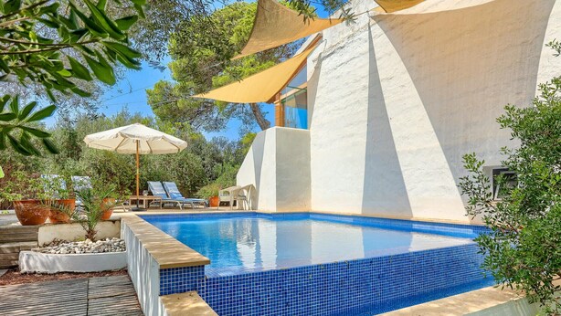 A swimming pool with blue tiles, surrounded by a wooden deck and potted plants. - Cas Predi by Rentallorca (Can Picafort)