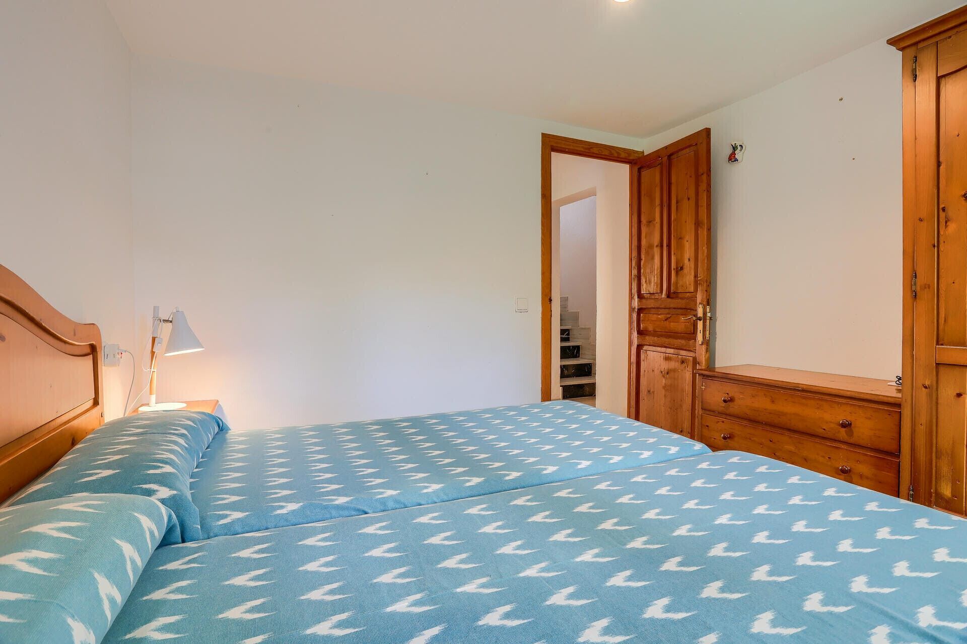 Ein Schlafzimmer mit einem Bett, einem Nachttisch, einer Lampe und Holzmöbeln.