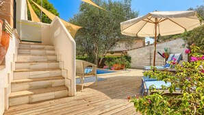 A wooden deck with a pool, outdoor furniture, and a staircase leading to a building. - Cas Predi by Rentallorca (Can Picafort)