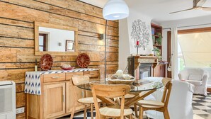 A dining area with a wooden wall, a glass table, and wooden chairs. - Cas Predi by Rentallorca (Can Picafort)