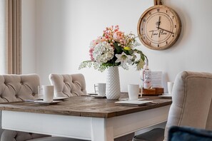 Uma mesa de jantar com um vaso de flores, um relógio e um cardápio.