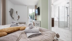 Una camera d'albergo con un letto, una TV, un bagno con doccia e un balcone con vista.