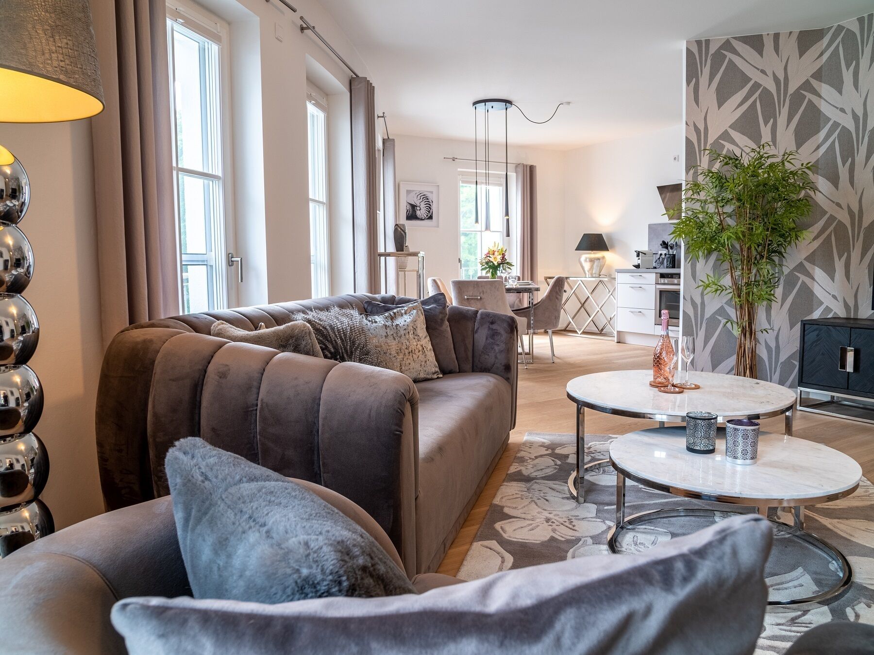 A modern living room with a brown sofa, a round coffee table, and a dining area in the background.