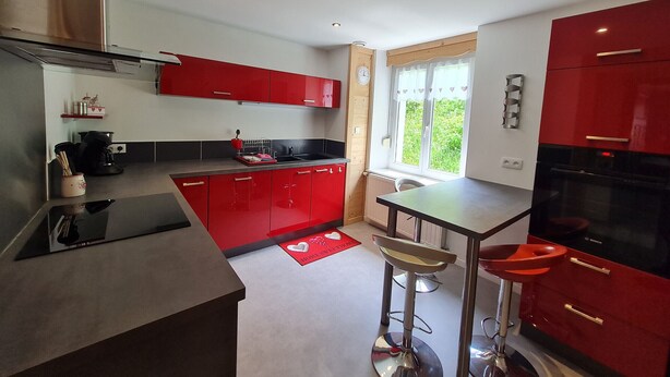 Una cocina moderna con armarios rojos, un horno Bosch negro y un ventanal con vistas a zonas verdes.