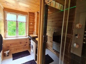 A wooden cabin bathroom with a window, sink, washing machine, and shower. - Cozy 85m² Apartment, Near Ski Trails & Nature, Fully Equipped, Parking, WiFi, Sleeps 8 (La Bresse)