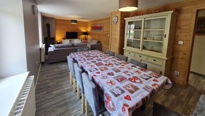 Una sala de estar acogedora con un sofá, un televisor y una mesa de comedor con mantel estampado.
