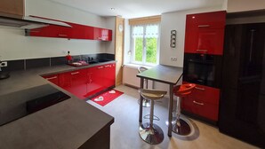Una cocina moderna con armarios rojos, una estufa negra y una ventana con vistas a la vegetación.
