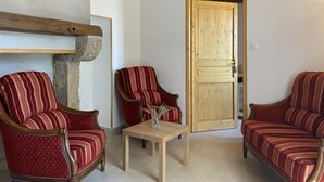 A room with two red upholstered chairs, a wooden table, and a wooden door.